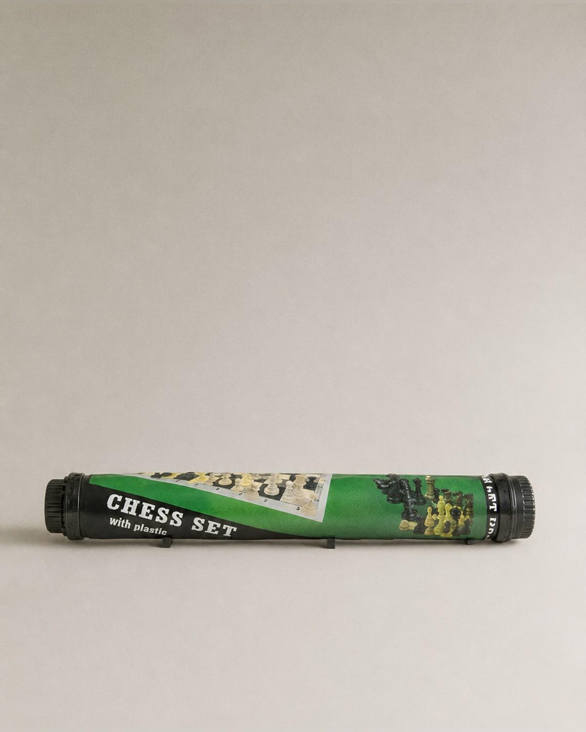 A cylindrical black and green tube lying on its side, printed with a photograph of a chess board and pieces and the words CHESS SET with plastic, a screw cap at each end.