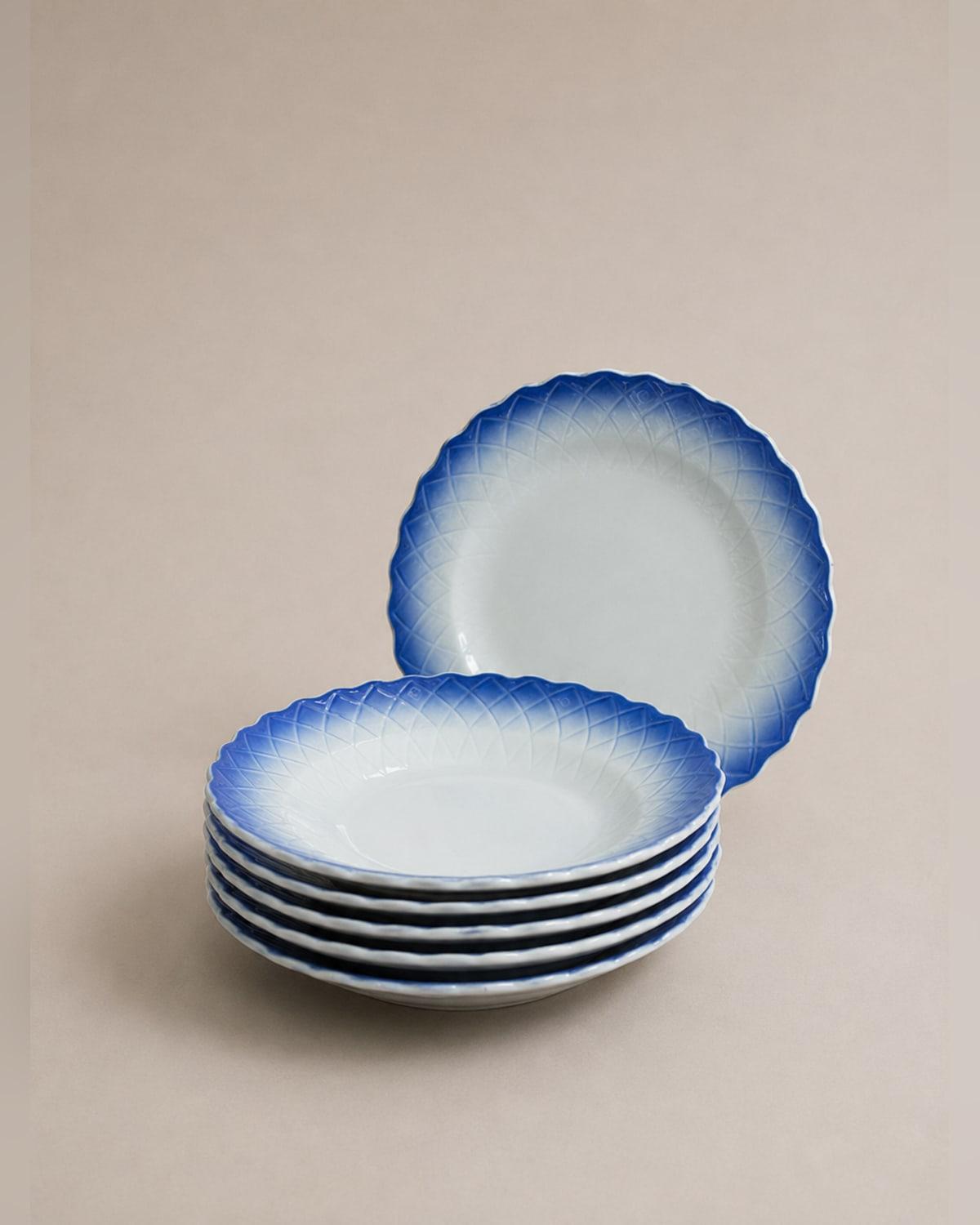 Six shallow porcelain bowls with a scalloped edge, each fading from deep cobalt at the rim to white at the centre, with a moulded lattice pattern in the border.